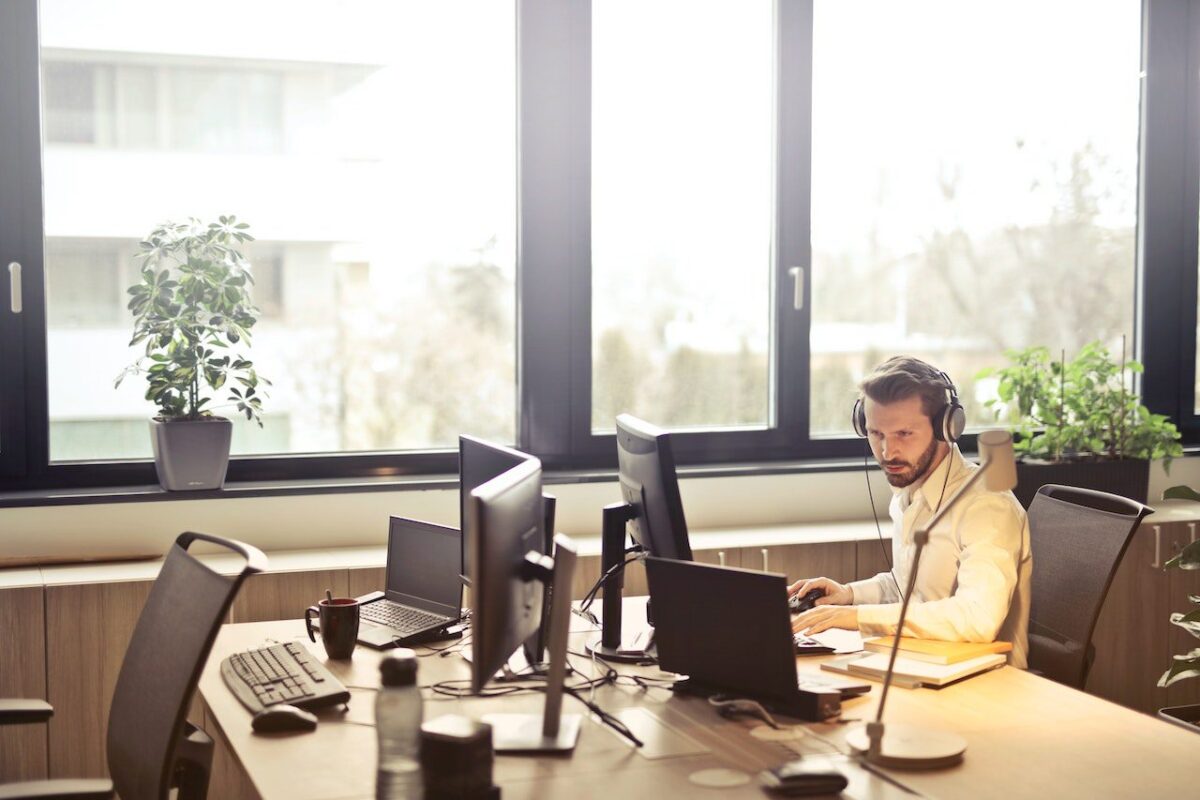 Employee working at his computer desk wearing headphones